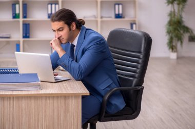 Genç erkek çalışan ofiste oturuyor.