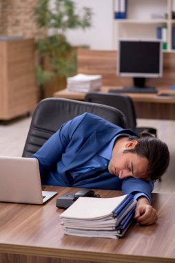 Genç bir erkek çalışan ve ofiste bir sürü iş var.