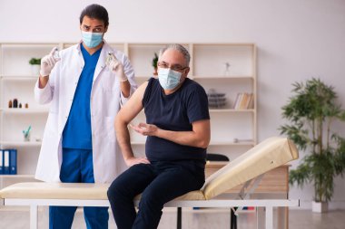 Yaşlı adam covid-19 aşı konseptinde genç doktoru ziyaret ediyor.