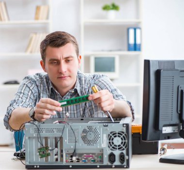 Genç teknisyen atölyede bilgisayar tamir ediyor.