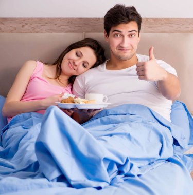 Mutlu bir aile yatakta kahvaltı yapıyor.