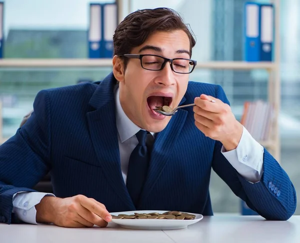 Funny businessman eating gold coins in office