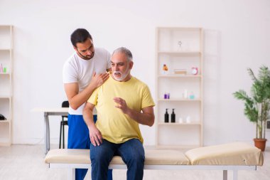 Yaşlı erkek hasta, genç erkek doktor masörünü ziyaret ediyor.