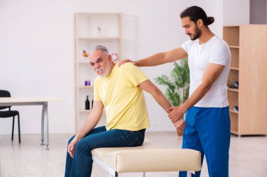 Yaşlı erkek hasta, genç erkek doktor masörünü ziyaret ediyor.