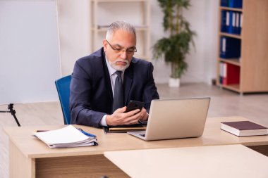 Eski erkek işveren ofiste oturuyor.