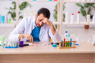 Genç erkek kimyager laboratuarda sabun test ediyor.