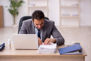 Ofisteki aşırı işten memnun olmayan genç bir erkek işçi.