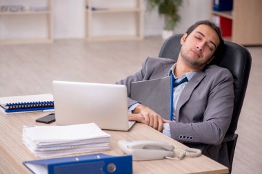 Ofisteki aşırı işten memnun olmayan genç bir erkek işçi.