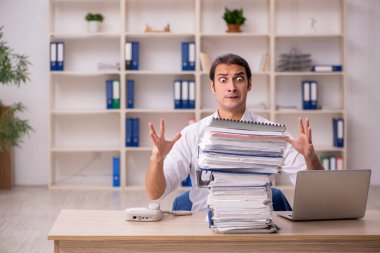 Genç bir erkek çalışan ve ofiste bir sürü iş var.