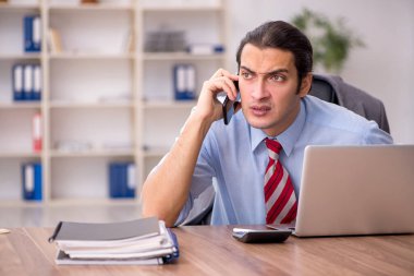 Genç erkek çalışan işyerinde oturuyor.