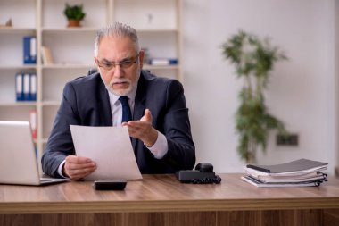 Ofiste çalışan yaşlı bir erkek.