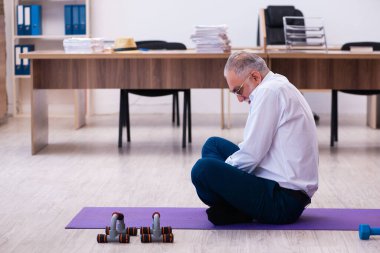 Ofiste spor egzersizleri yapan eski bir işadamı.