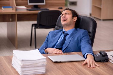 Genç bir erkek çalışan ve ofiste bir sürü iş var.