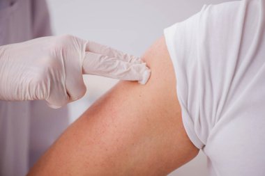 Genç erkek hasta yaşlı erkek doktoru aşıyla ziyaret ediyor.