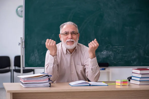 Old male teacher sitting in the classroom