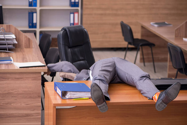 Young male employee sleeping at workplace