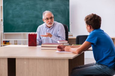 Yaşlı erkek öğretmen ve okul çocuğu sınıfta.