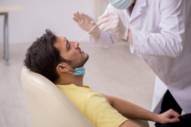 Genç erkek hasta yaşlı doktor otorhinolaryngologis 'i ziyaret ediyor.