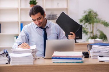 Genç bir erkek çalışan ve ofiste çok fazla iş var.