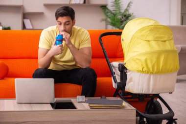 Genç adam evde yeni doğan çocuğa bakıyor.