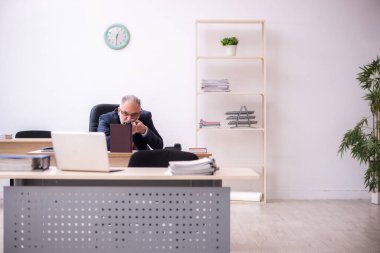 Ofiste tüfeği tutan eski bir işadamı.