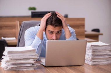 Ofisteki aşırı işten memnun olmayan genç bir erkek işçi.