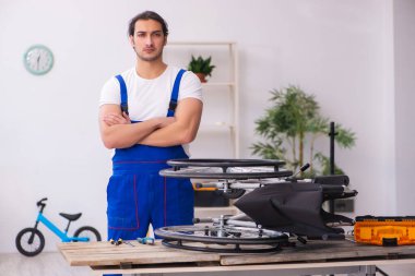 Genç erkek tamirci içeride tekerlekli sandalyeyi tamir ediyor.