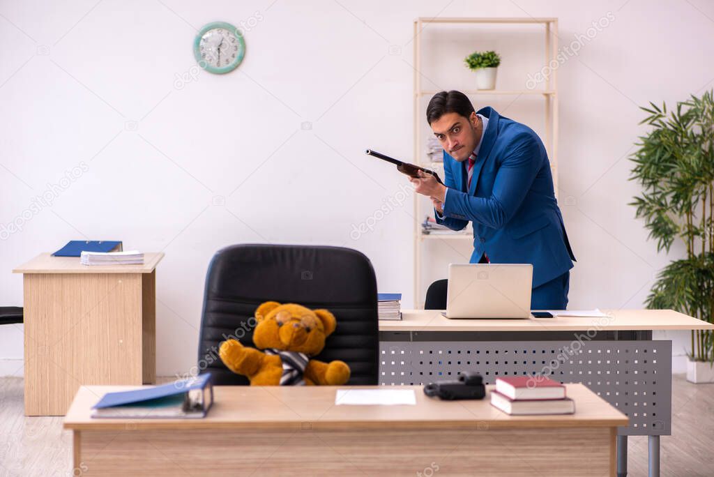 Young male employee and his toy bear boss in funny concept