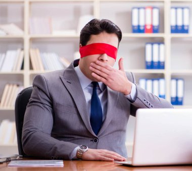 Ofiste masasında oturan gözü bağlı iş adamı.