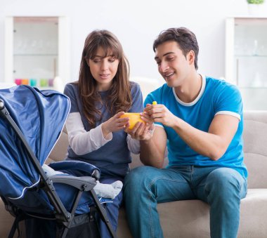 Bebekleri bebek arabasında oturan genç ebeveynler.