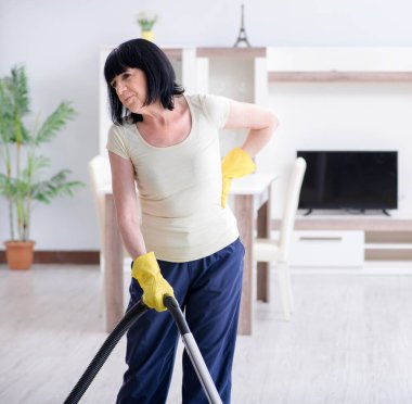 Yaşlı kadın elektrik süpürgesinden yorgun düştü.