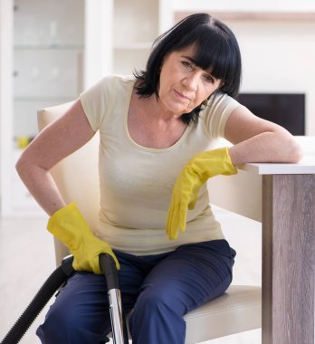 Yaşlı kadın elektrik süpürgesinden yorgun düştü.