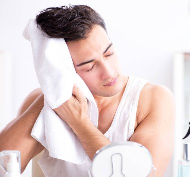 Genç yakışıklı adam aynaya bakıyor.