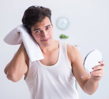 Genç yakışıklı adam aynaya bakıyor.