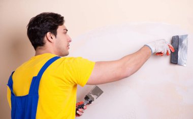 Duvara alçı yapıştıran genç müteahhit.