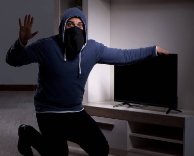 Hırsız, apartmandan televizyon çalıyor.