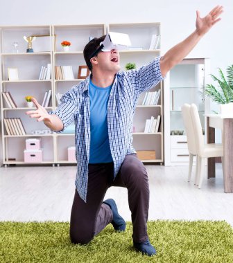 Evde sanal gerçeklik gözlüklü bir adam oynuyor.