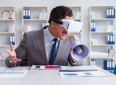 Ofiste sanal gerçeklik gözlüklü bir iş adamı var.