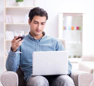 Genç adam evde şarap içiyor.