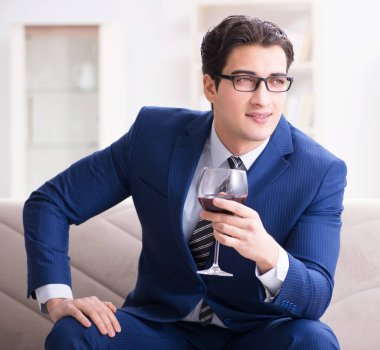 İş adamı evde oturmuş şarap içiyor.