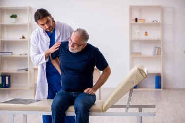 Yaşlı erkek hasta, genç erkek doktor masörünü ziyaret ediyor.