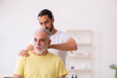 Yaşlı erkek hasta, genç erkek doktor masörünü ziyaret ediyor.