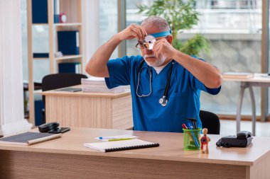 Klinikte çalışan yaşlı bir erkek laringolog.