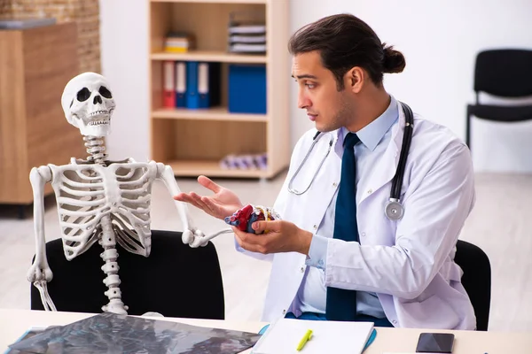 Joven médico cardiólogo y paciente esqueleto en las clínicas — Foto de Stock