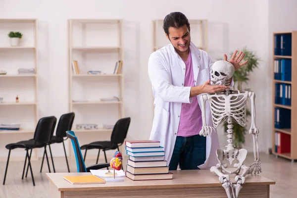 Fiatal férfi orvos diák tanul emberi csontváz az osztályteremben — Stock Fotó