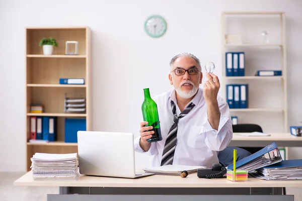 Alte männliche Angestellte trinkt Alkohol im Büro — Stockfoto