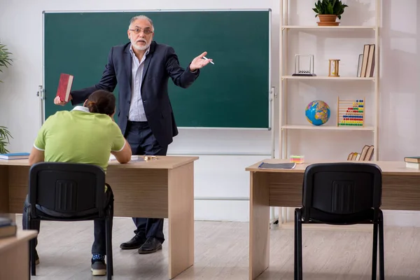 Aged teacher and male lazy student in the classroom