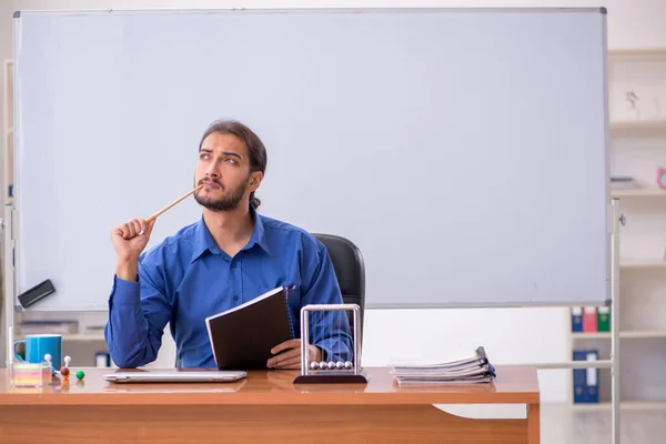 Fiatal férfi tanár fizikus ül az osztályteremben — Stock Fotó