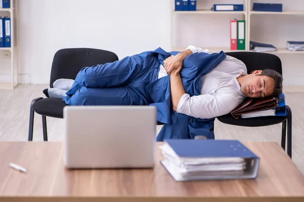 Молодой работник спит в офисе на стульях — стоковое фото