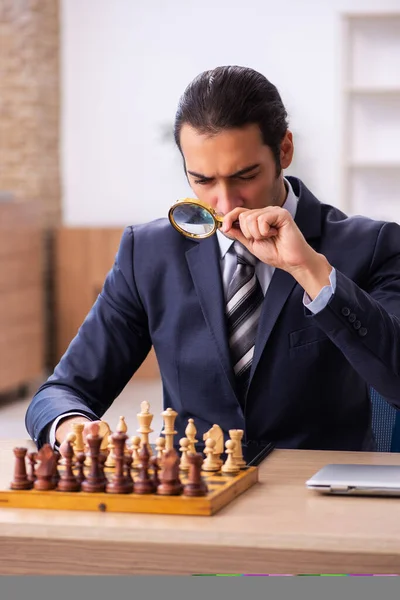 Joven empleado masculino jugando ajedrez en el lugar de trabajo — Foto de Stock